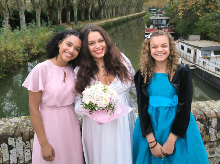woman in wedding dress and daughters standing on a bridge over Canal Du Midi, in Autumn